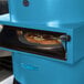 A blue TurboChef Fire countertop pizza oven with a round pizza inside.