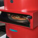 A TurboChef fire red electric countertop pizza oven with a pizza inside.