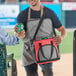 A man holding a Choice red insulated soft cooler bag.