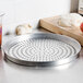 An American Metalcraft round metal pizza pan with perforations.