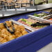 A navy blue Cambro buffet with food on a counter.