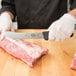 A person in gloves using a Victorinox narrow skinning knife to cut meat on a counter.
