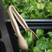 A pair of Cambro beige plastic tongs in a container of spinach.