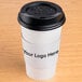 A white paper coffee cup with a black sleeve.