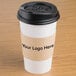 A natural Kraft coffee cup sleeve on a coffee cup with a black plastic lid.