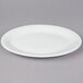 A white Tuxton narrow rim oval china platter on a gray surface.