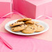 A Tuxton bright white oval china platter with a stack of chocolate chip cookies on a pink ribbon.