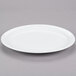 A white Tuxton China oval platter with a narrow rim on a gray surface.