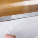 A hand using a Bulman white plastic film dispenser to cut plastic wrap.