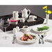 A Homer Laughlin Ameriwhite china platter with meat and vegetables on a table with wine and coffee.