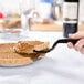 A hand using a Visions black plastic pie server to cut a piece of pie.