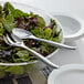 A bowl of salad with Visions heavy weight silver plastic serving spoons.
