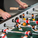 A close up of people playing foosball on an Atomic Gladiator foosball table.