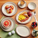 A table set with Acopa brown speckle narrow rim stoneware plates filled with food and fruit.