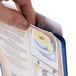 A hand holding a Menu Solutions Royal Blue Hamilton heat sealed menu board.