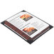 A black Menu Solutions Kearny menu board on a table with a menu inside.