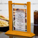 A Menu Solutions oak wood flip top table tent on a table with a menu.