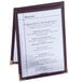 A burgundy Menu Solutions table tent holding a white menu on a table.