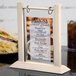 A Menu Solutions wood flip top table tent on a table with a menu.