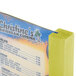 A Menu Solutions lime wood table tent with a yellow menu card on a table.