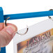 A hand using a Menu Solutions True Blue wood flip top table tent clip.