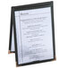 A Menu Solutions black sewn edge table tent holding a black and white menu on a table.