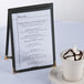 A Menu Solutions black sewn edge table tent on a table with a cup of ice cream.