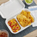 A white EcoChoice takeout container with two compartments, one filled with food.