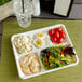 A white EcoChoice bagasse tray with a salad, cucumber, tomato, and a glass of water.
