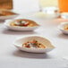 EcoChoice Bagasse Leaf Appetizer Dishes with food on a table.