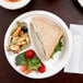A white EcoChoice Compostable Sugarcane plate with a sandwich and vegetables on it.