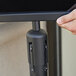 A hand using a black Aarco stanchion sign frame on a table.