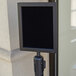 A black Aarco stanchion sign frame holding a black square sign.