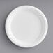 A close up of an EcoChoice Compostable Sugarcane Bagasse plate with a white rim on a gray surface.