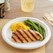 A plate of food with a chicken breast and green beans on a table.