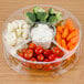 A Polar Pak clear plastic round catering tray with 5 compartments filled with vegetables and white sauce with a lid.