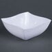 A white bowl with a wavy edge on a gray surface.