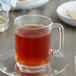 A glass cup of Caffe De Aroma Earl Grey tea on a plate.
