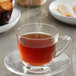 A Caffe De Aroma English Breakfast tea single serve cup on a saucer with a glass cup of tea.
