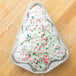 A Christmas tree shaped cake in a Durable Packaging Christmas tree foil pan.