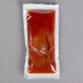 An Americana ketchup portion packet on a gray surface.