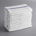 A stack of white kitchen towels with blue stripes.