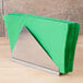 A Tablecraft stainless steel napkin holder with green napkins on a wood surface.