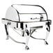 A silver stainless steel square roll top chafer on a table with legs.