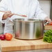 A chef using a Vollrath stainless steel sauce pot on a counter.