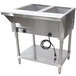 An Advance Tabco electric steam table with two stainless steel food pans on a stainless steel counter with an undershelf.