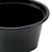 A Newspring black plastic oval souffle container with a lid.