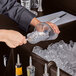 A person pouring ice into a glass at a Cambro portable bar.