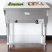 An Advance Tabco stainless steel electric hot food table with two pans of food on a counter.