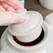 A hand pouring tea into a Hall China ivory teapot.